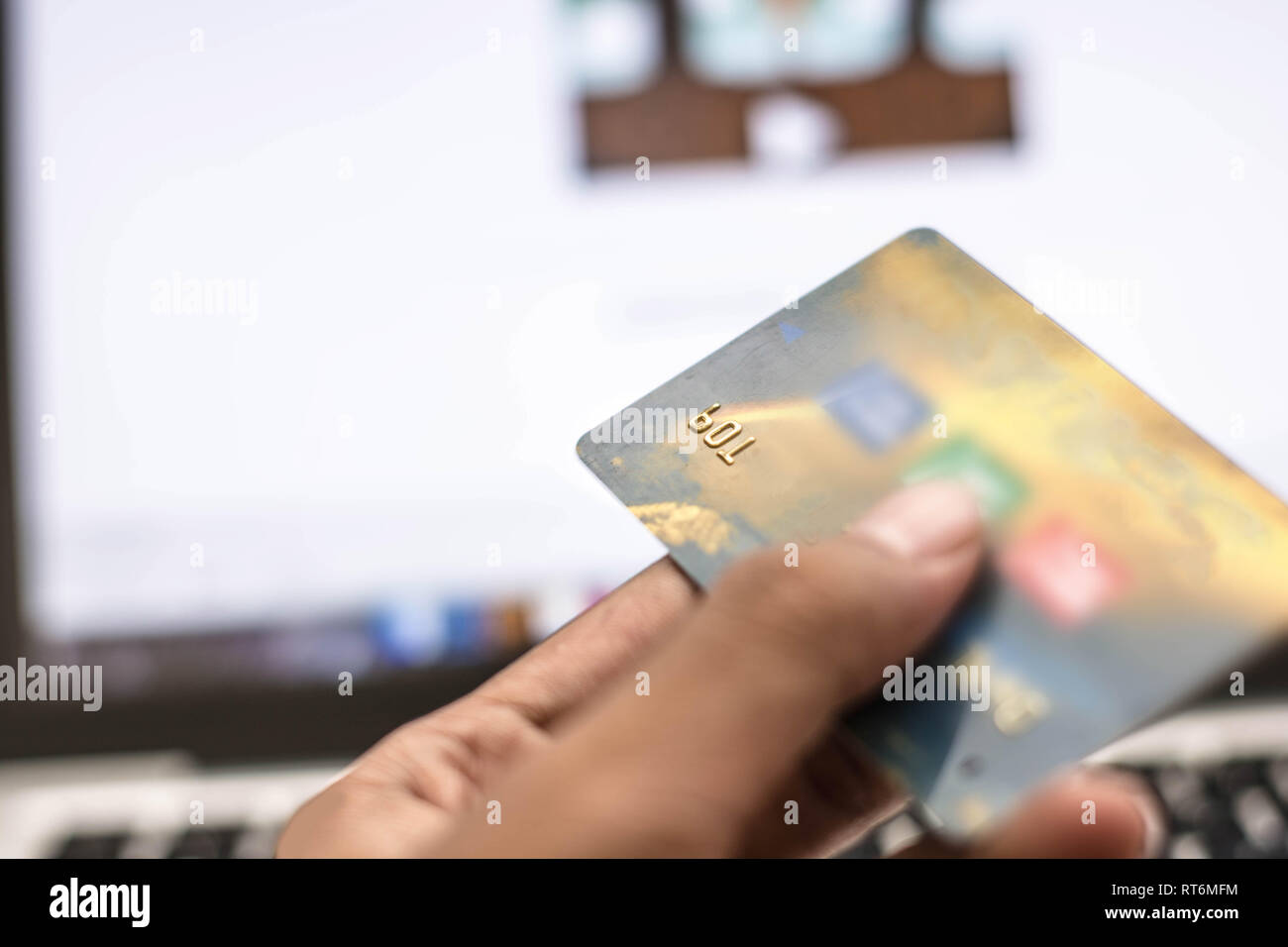 hand holding phone and internet security key and atm card with monitor showing internet transaction as background Stock Photo