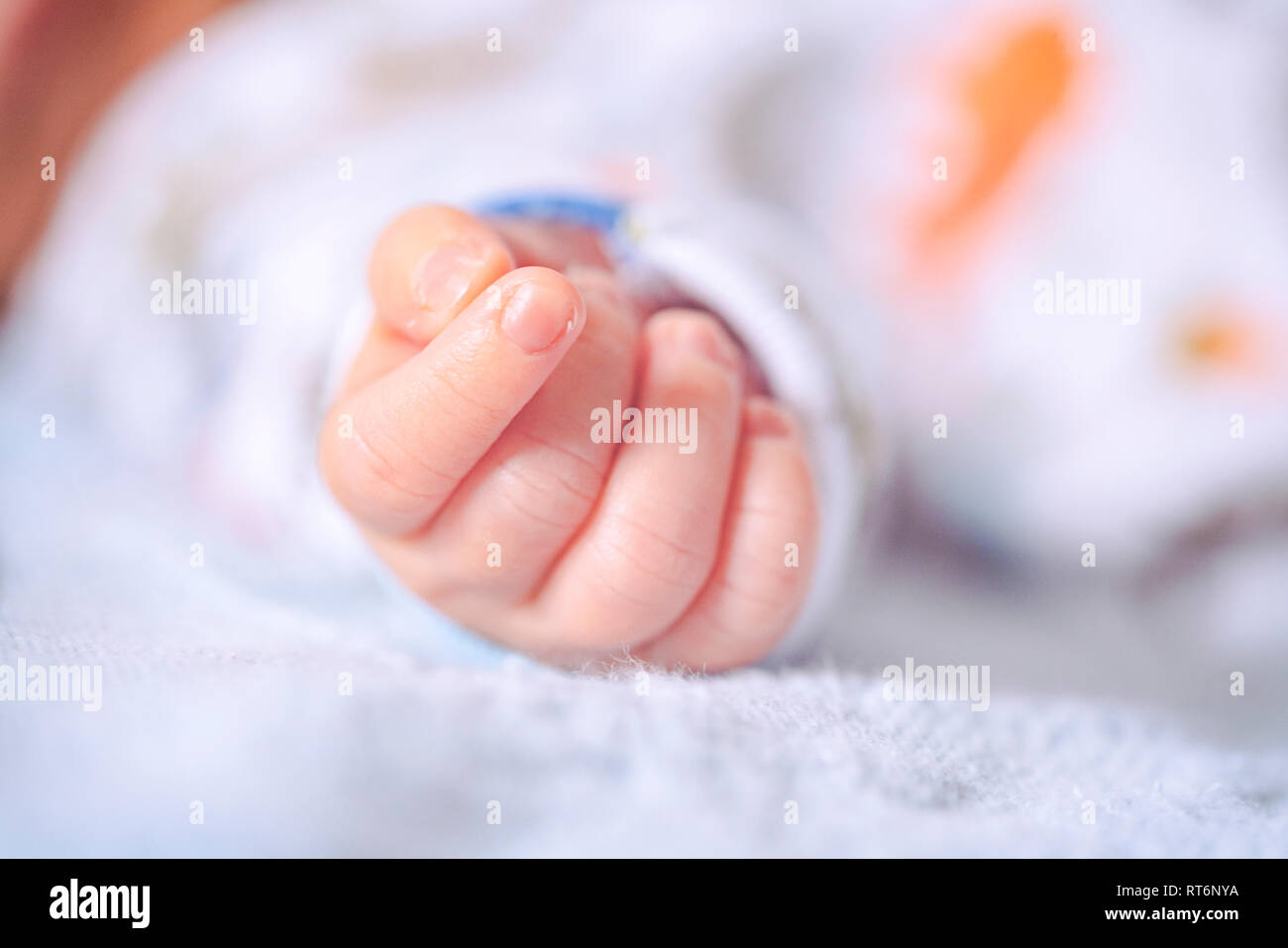 Newborn baby soft-focus tiny fist of an infant with a vintage analog Kodachrome feel. Happy Mothers Day Fathers Day new baby or parenting concept. Stock Photo