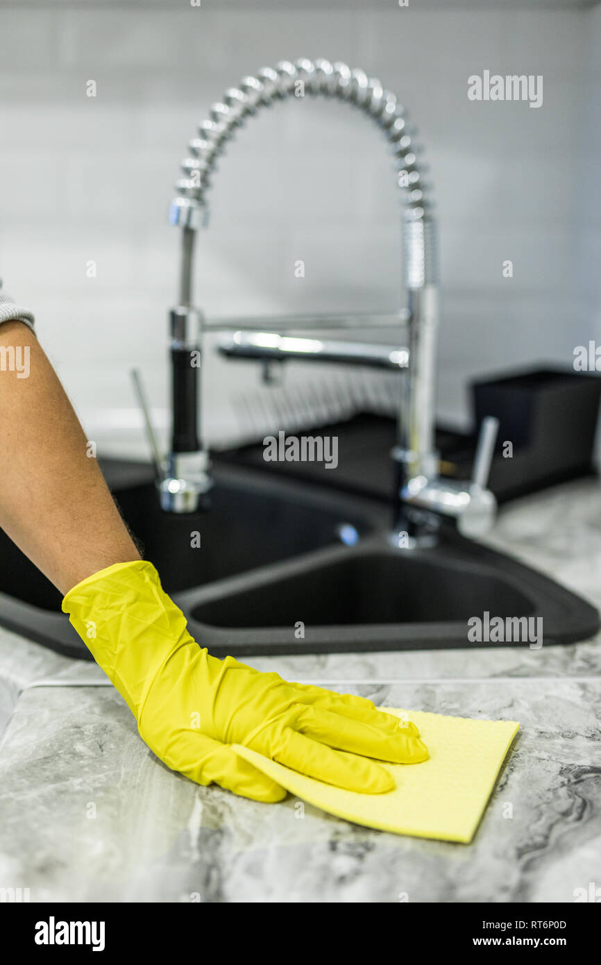 Cropped image of male janitor cleaning counter with detergent spray bottle and sponge Stock Photo