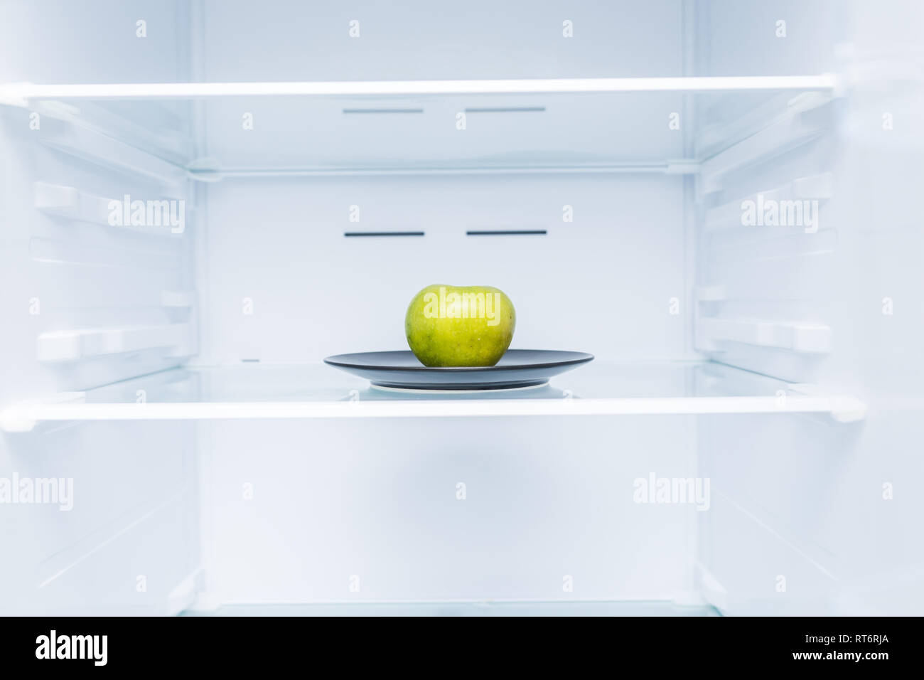 One apple in open empty refrigerator. Weight loss diet concept Stock
