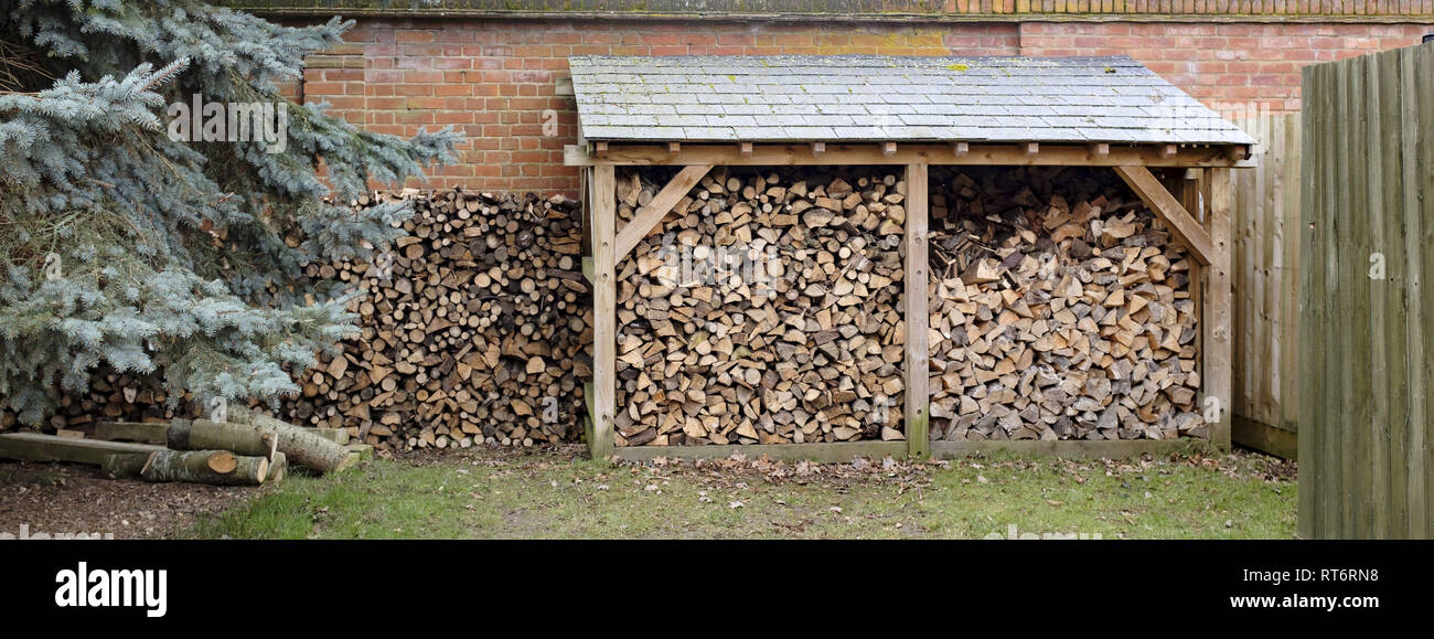 Log store and woodpile of cut firewood stored outdoors Stock Photo
