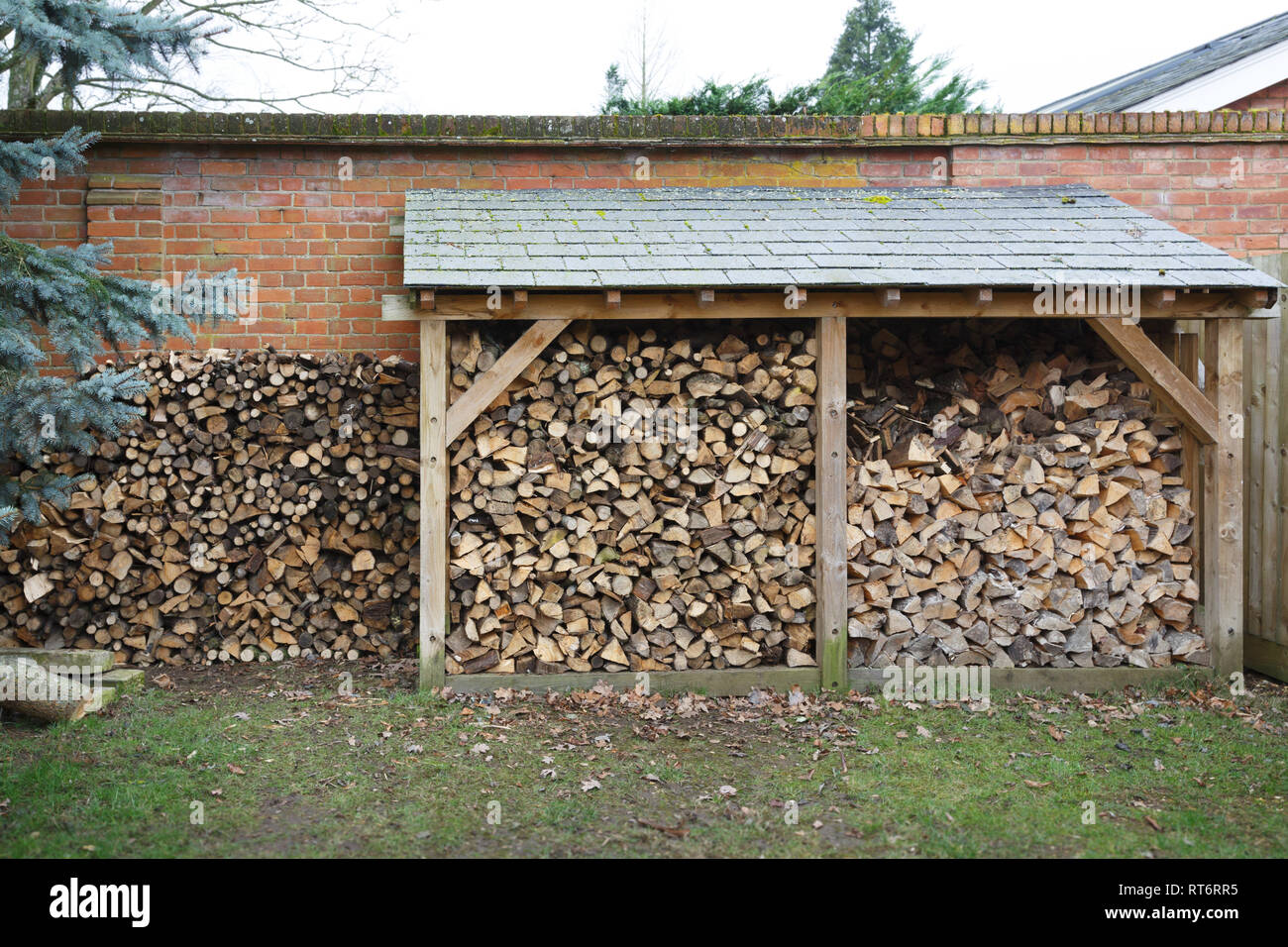 Log store filled with cut logs for firewood in a garden Stock Photo