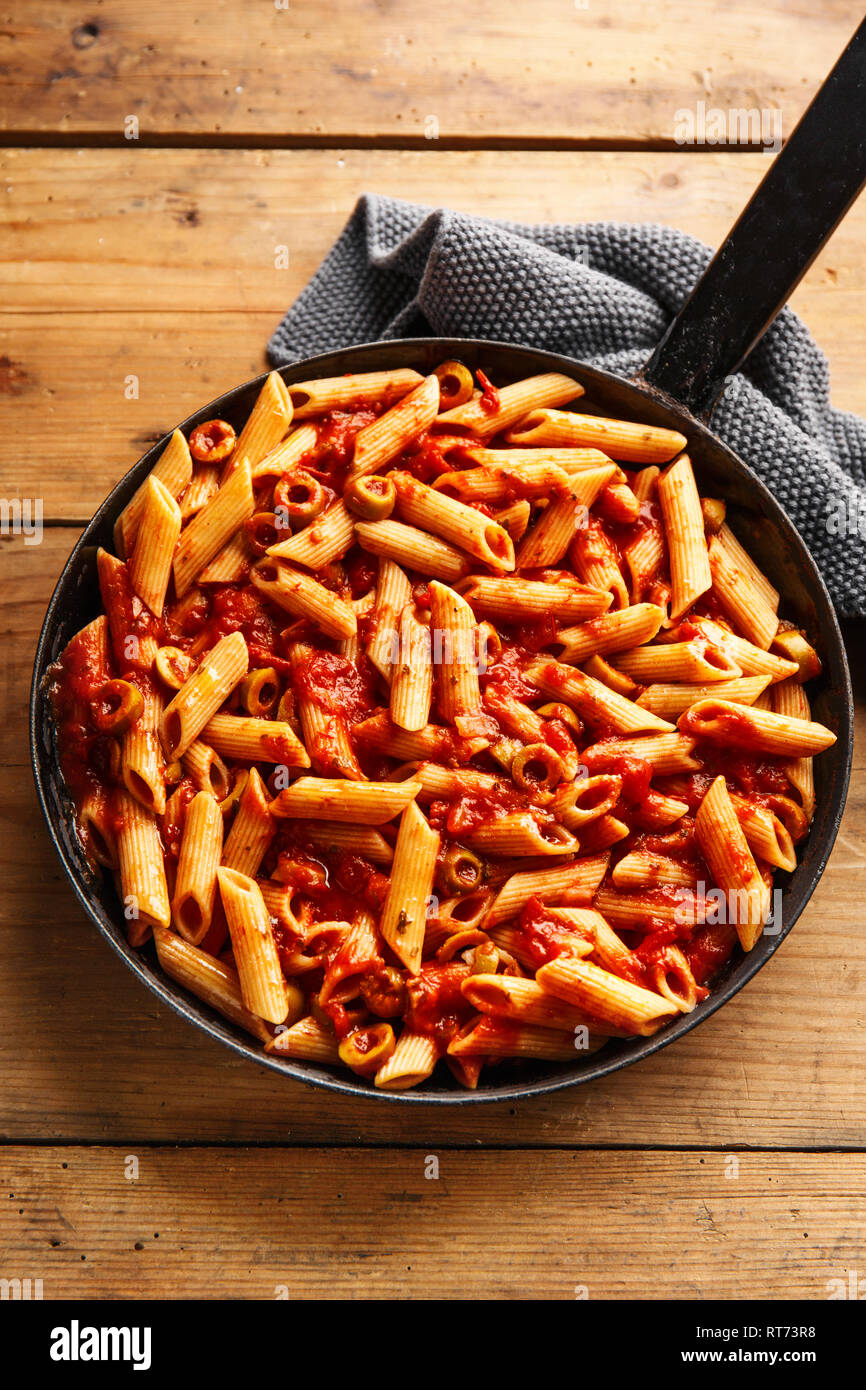 Tasty appetizing pasta penne with tomato sauce and olives served on pan.  Wooden background. Closeup Stock Photo - Alamy