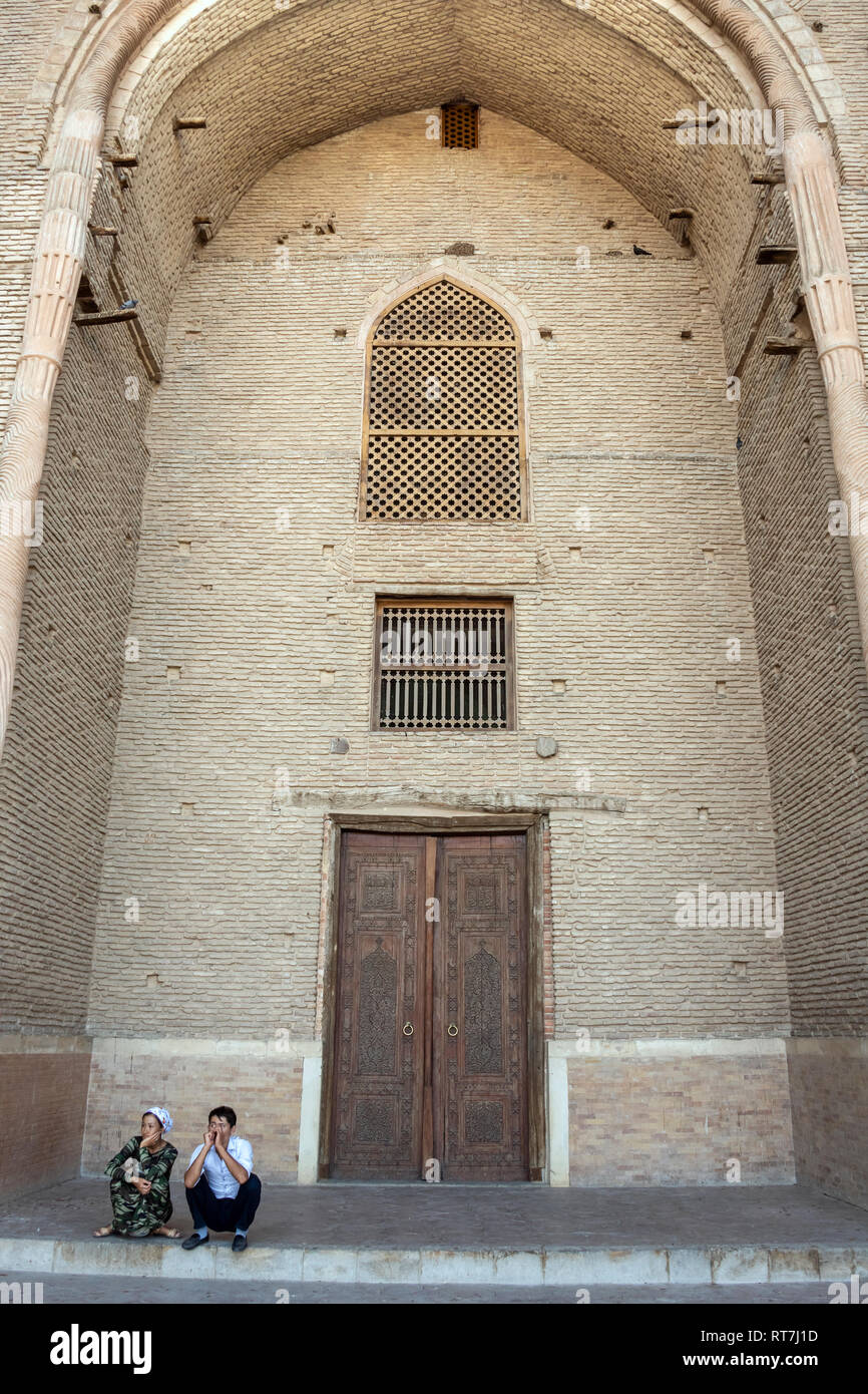 Main portal of the mausoleum of Khoja Ahmed Yasawi with couple squatting on the steps, Turkestan, Kazakhstan Stock Photo