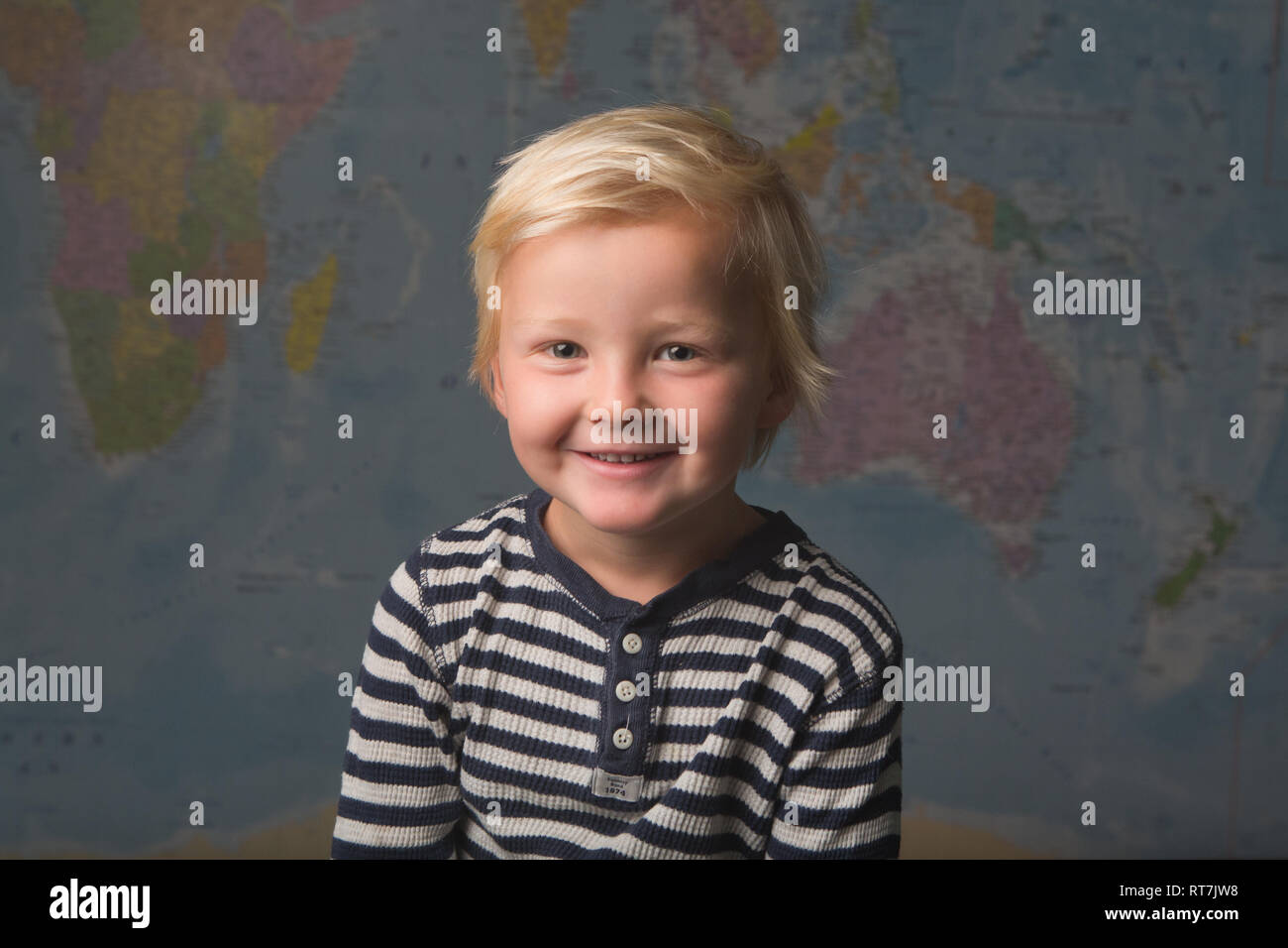 A happy child smiles in front of a world map Stock Photo