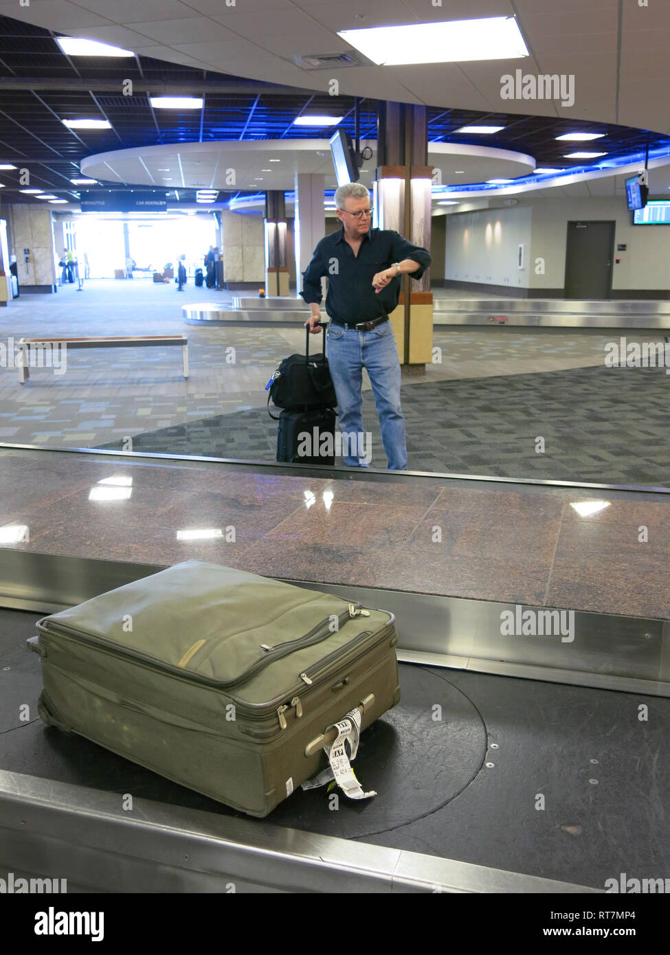 Traveler Waiting for Lost Suitcase at Airport Baggage Claim Area, USA