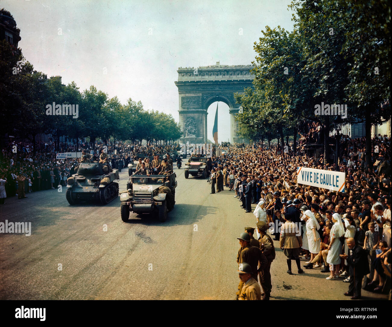 Crowds of French patriots line the Champs Elysees to view Allied tanks and half tracks pass through the Arc du Triomphe, after Paris was liberated on August 25, 1944 Stock Photo