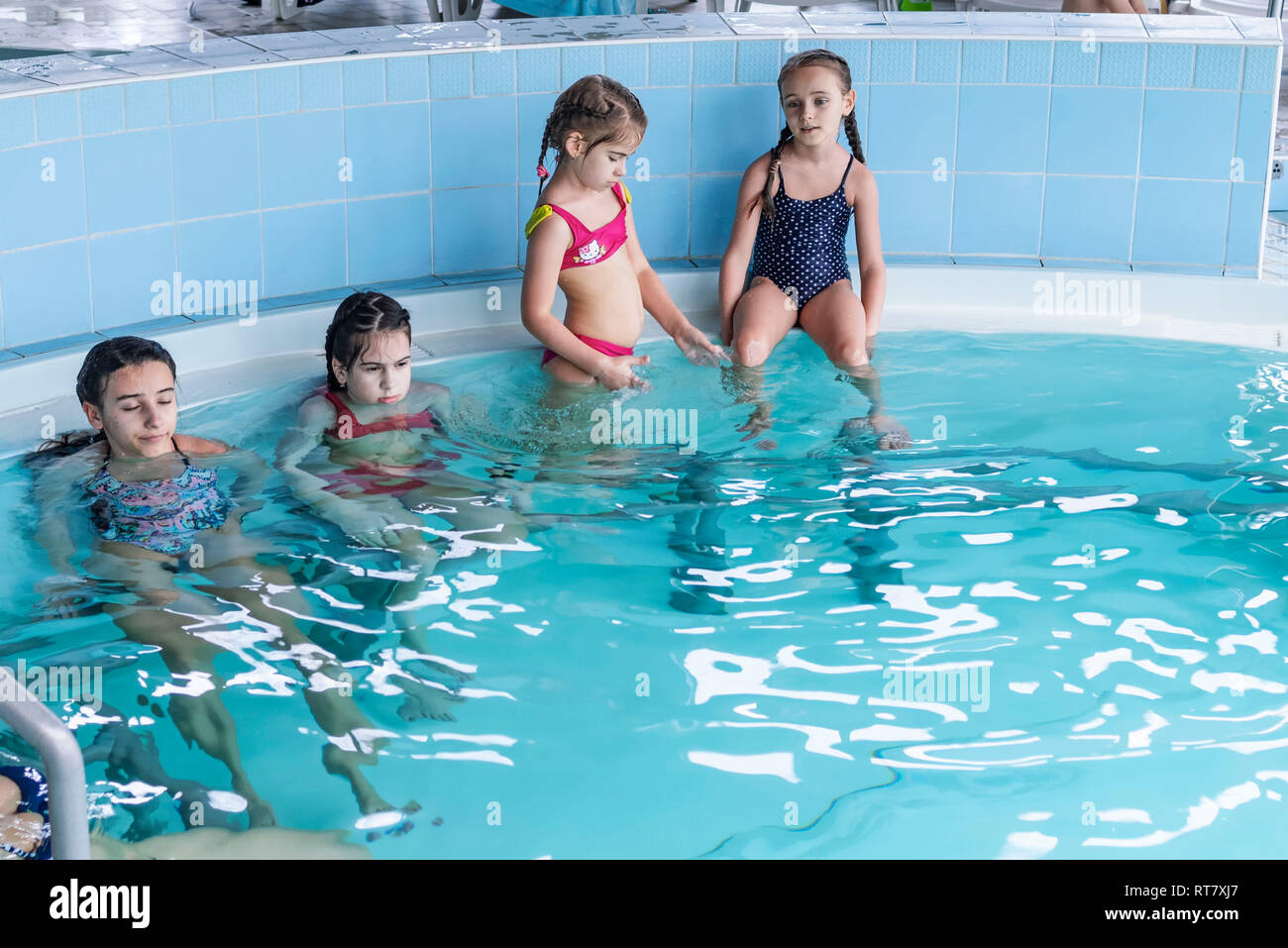 Happy girls play in the pool.Beautiful girls swim and having fun in water.Active holiday.Girls swim in the pool. Stock Photo