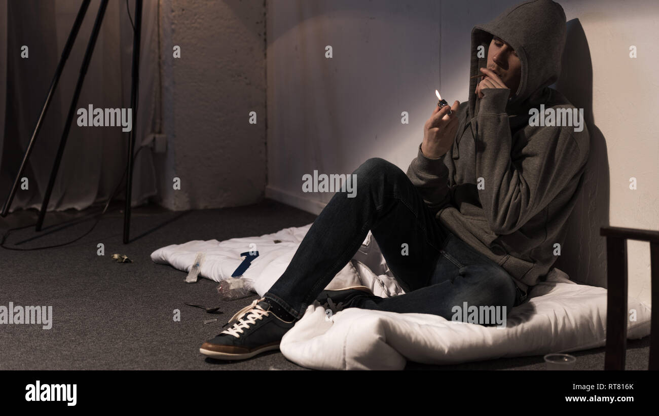 junkie man smoking marijuana rolled cigarette white sitting on mattress on floor Stock Photo Alamy