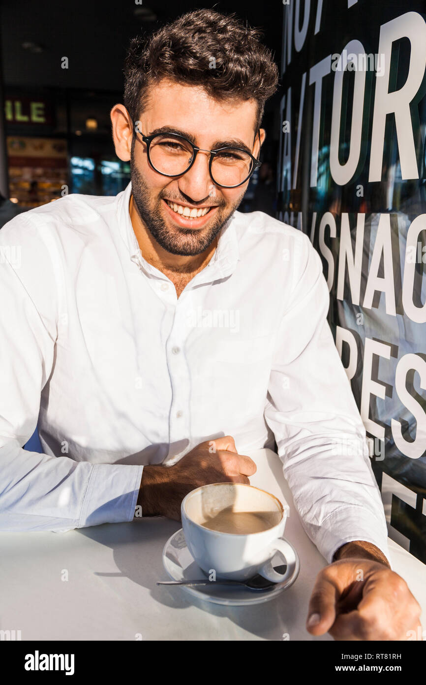 Portrait of laughing young businessman drinking coffee at sidewalk cafe Stock Photo