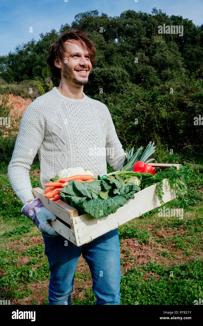 Man carrying crate with freshly harvested vegetables from his vegetable garden Stock Photo