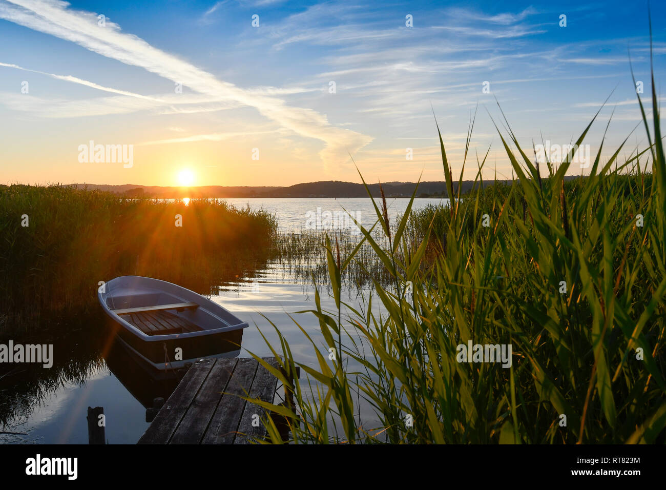 Germany, Mecklenburg-Western Pomerania, Ruegen, Sellin, empty rowing boat near jetty at sunset Stock Photo