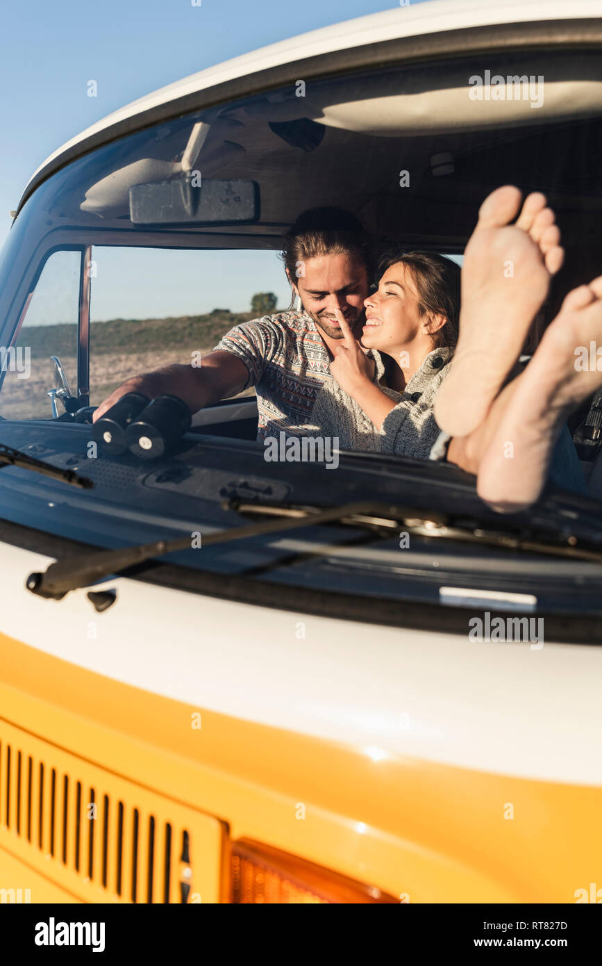 Happy couple sitting in their camper with bare feet up Stock Photo