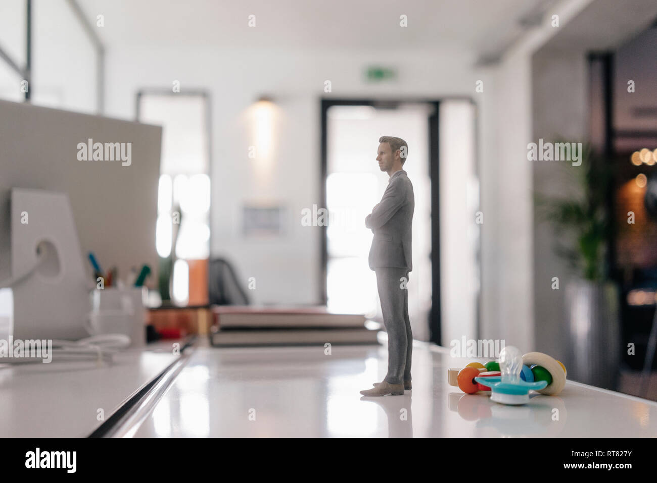 Businessman figurine standing on desk with pacifier and toys Stock Photo