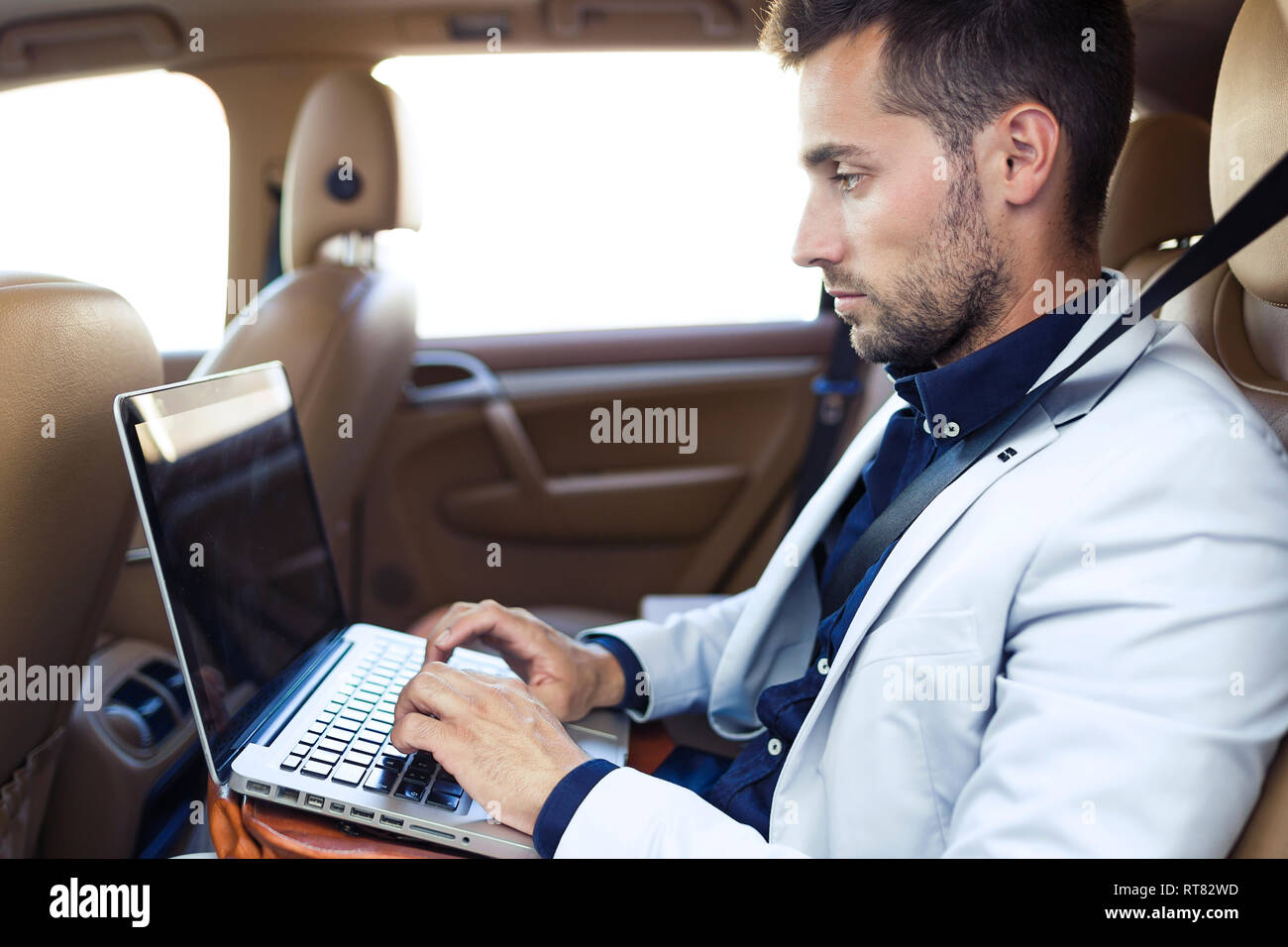 Young businessman working from the backseat of a car Stock Photo