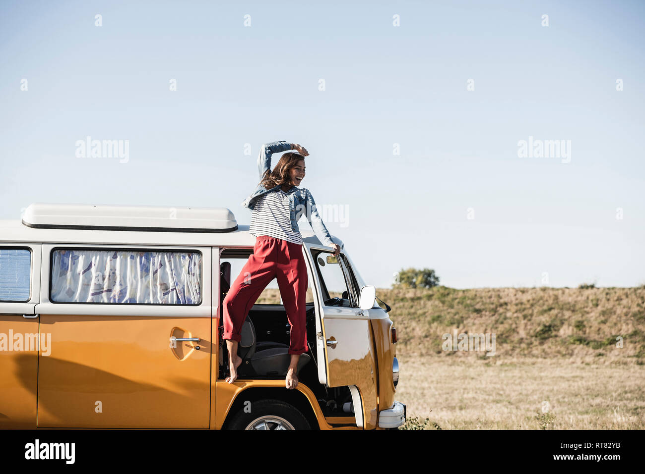 Pretty woman on a road trip with her camper, cheering, enjoying freedom ...