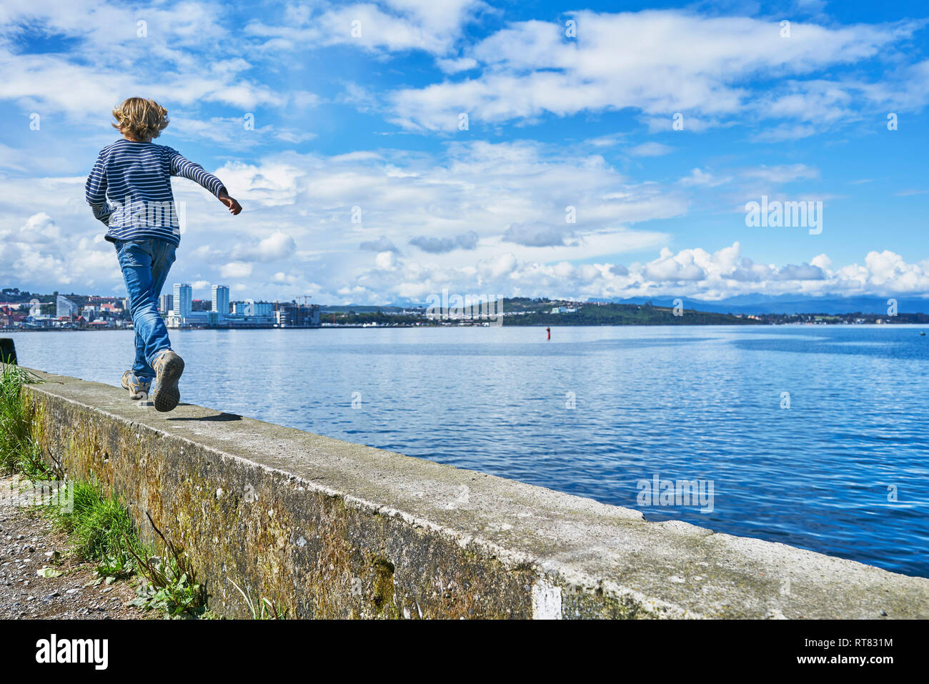 Chile, Puerto Montt, boy running on quay wall at the harbor Stock Photo