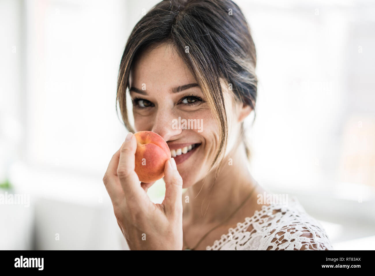 Laughing woman smelling an apricot Stock Photo