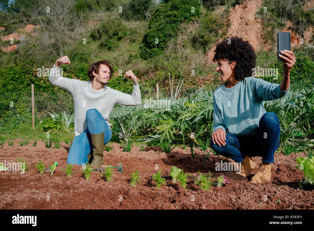 Couple taking selfies of planting lettuce seedlings in an vegetable garden Stock Photo