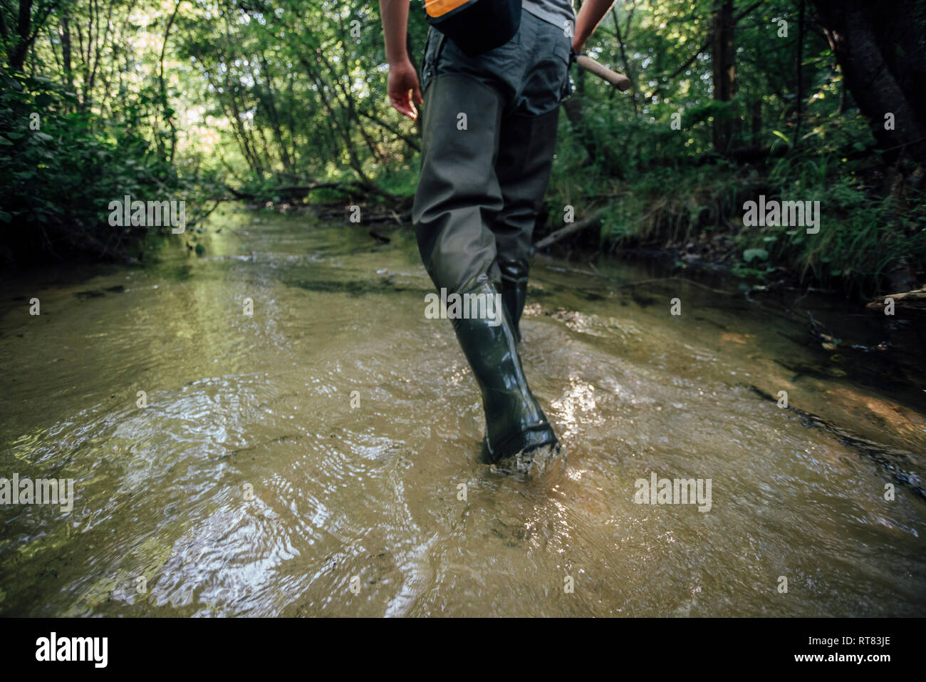 Back view of young angler wading in water, partial view Stock Photo