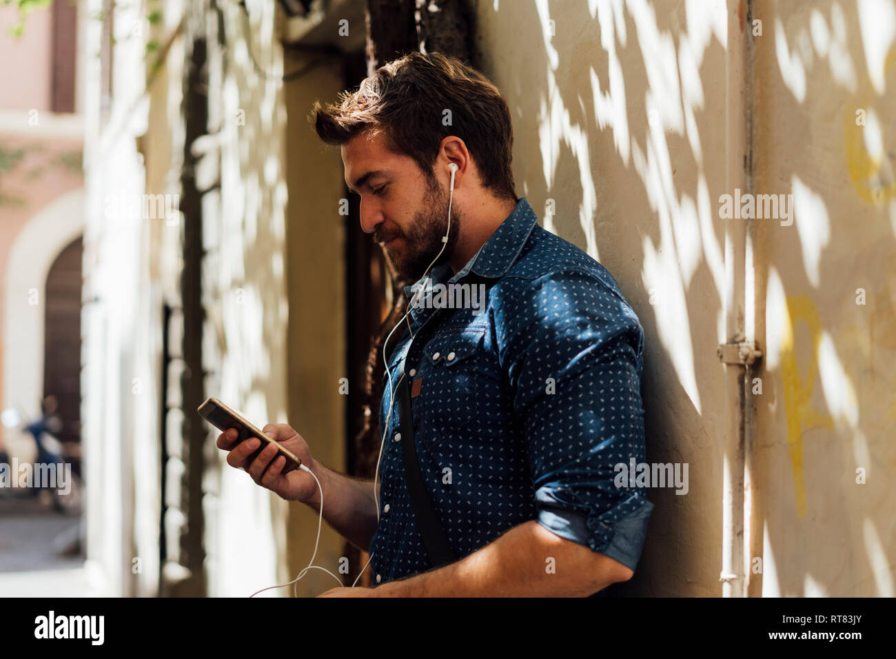 Man using earphones and smartphone outdoors Stock Photo