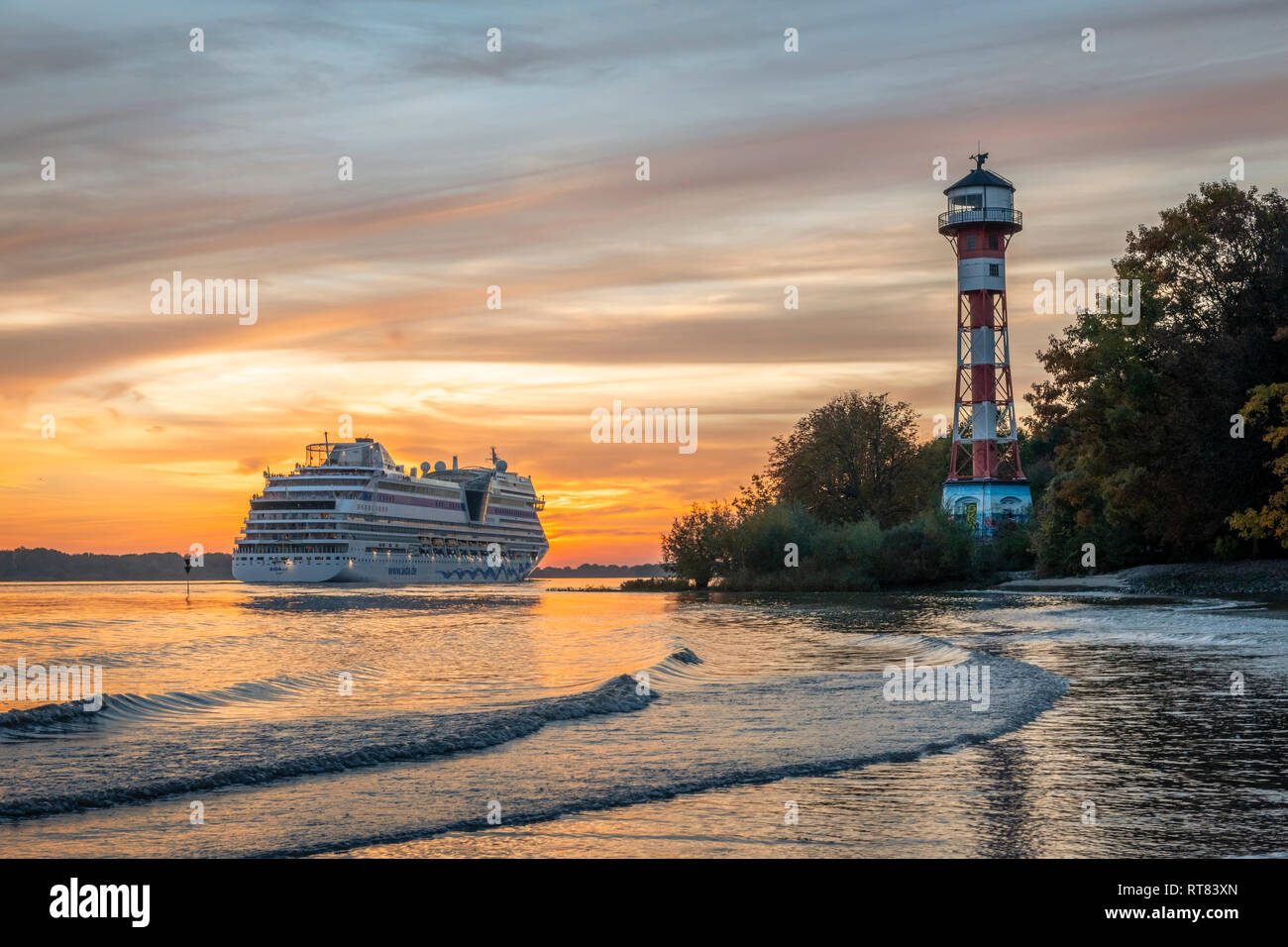 Germany, Hamburg, Rissen, Cruise liner and Wittenbergen lighthouse at sunset Stock Photo