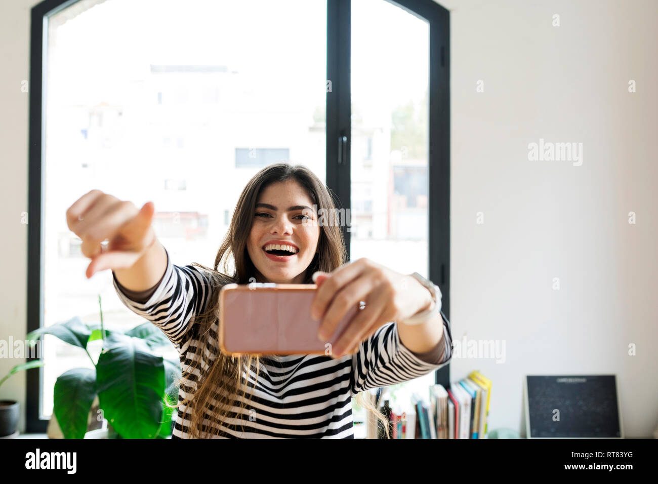 Happy young woman at home taking a selfie Stock Photo