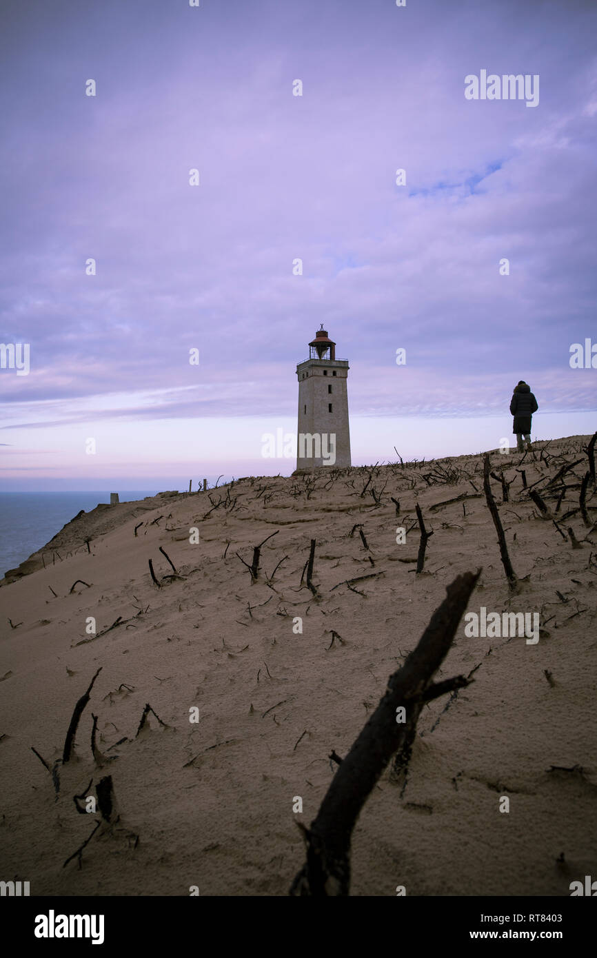 Denmark, North Jutland, back view of man looking at Rubjerg Knude Lighthouse at blue hour Stock Photo