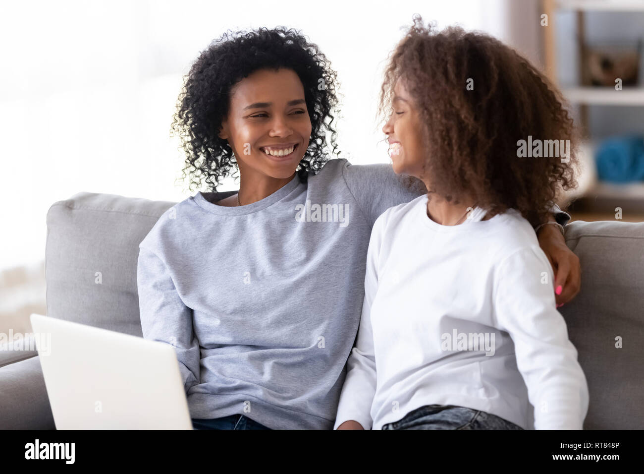 African mother and daughter sitting on couch using computer Stock Photo