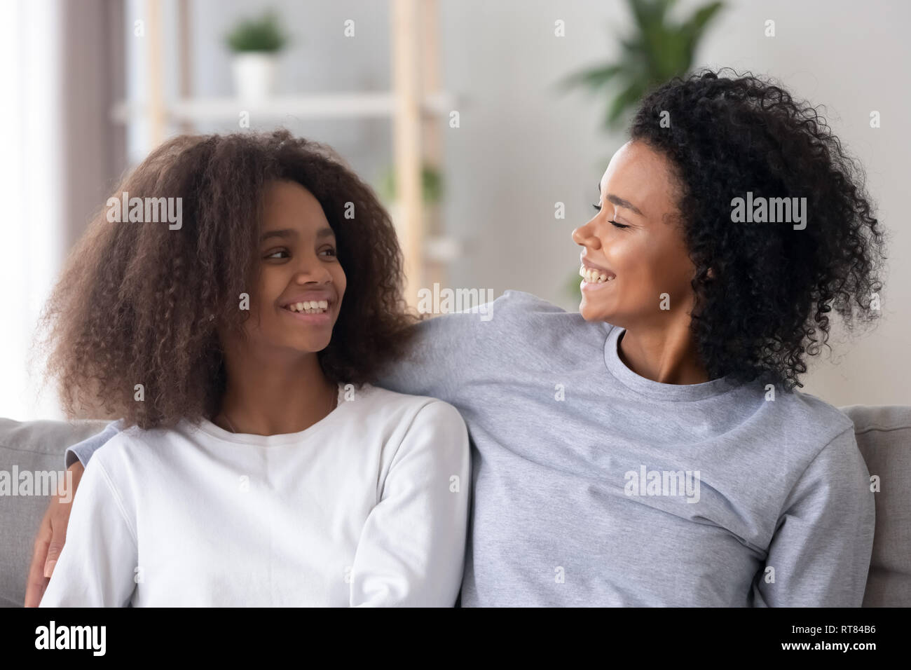 African loving mother embracing looking at adolescent daughter Stock Photo