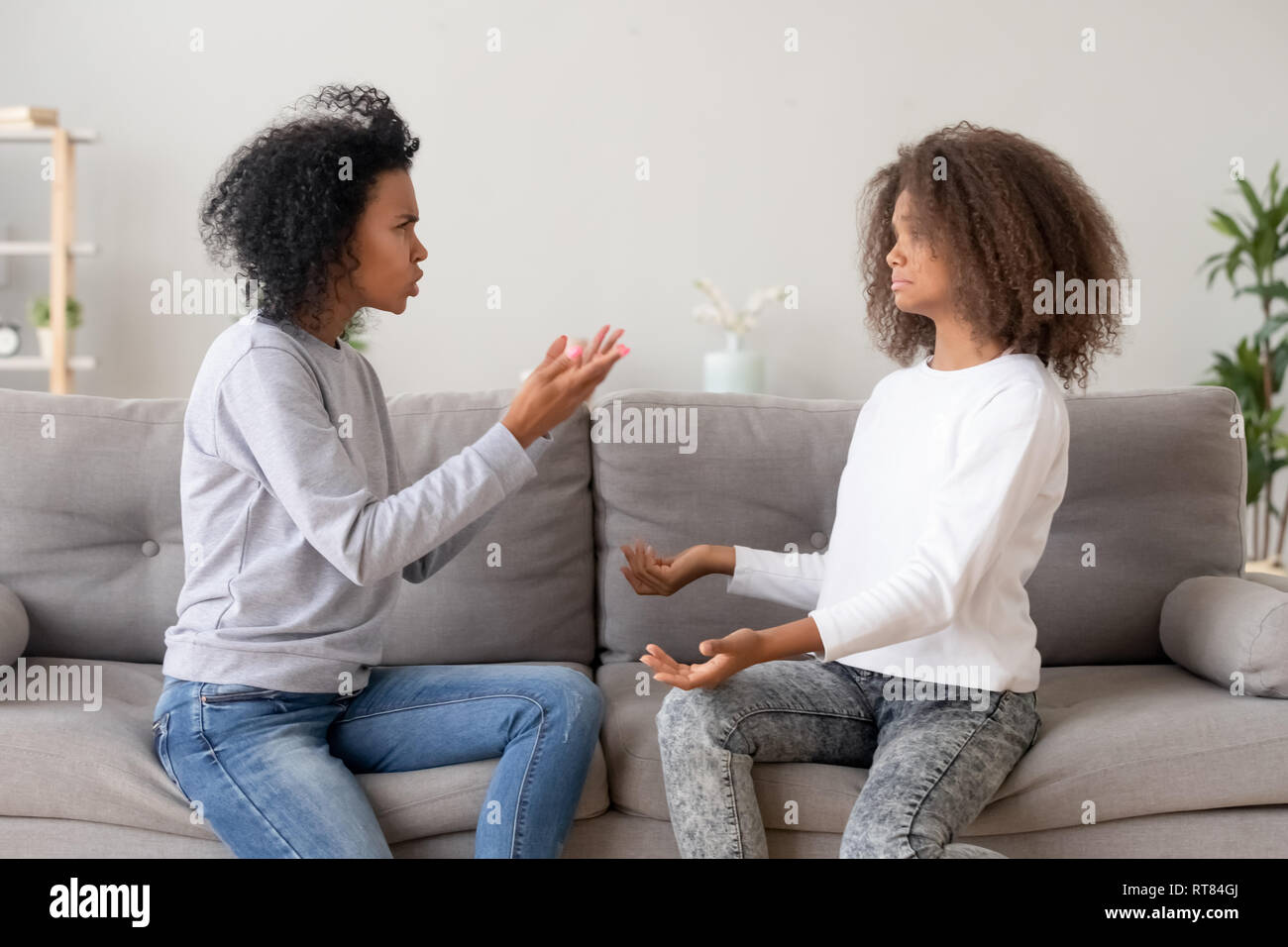 African mother scolding teen daughter sitting on couch at home Stock Photo