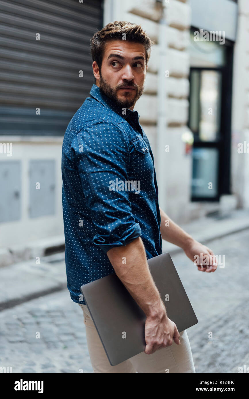 Portrait of businessman with laptop on the street watching something Stock Photo