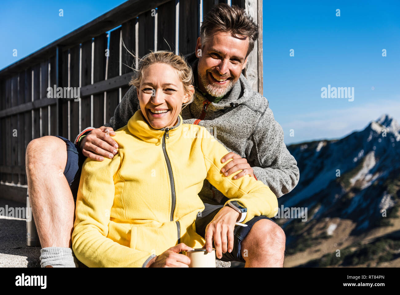 Hiking couple sitting in front of mountain hut, taking a break Stock Photo