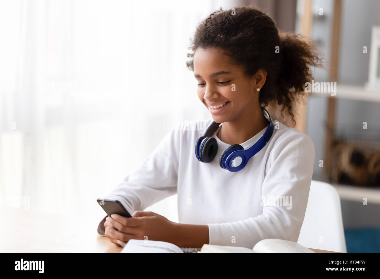 African teen girl distracted from study use smartphone Stock Photo