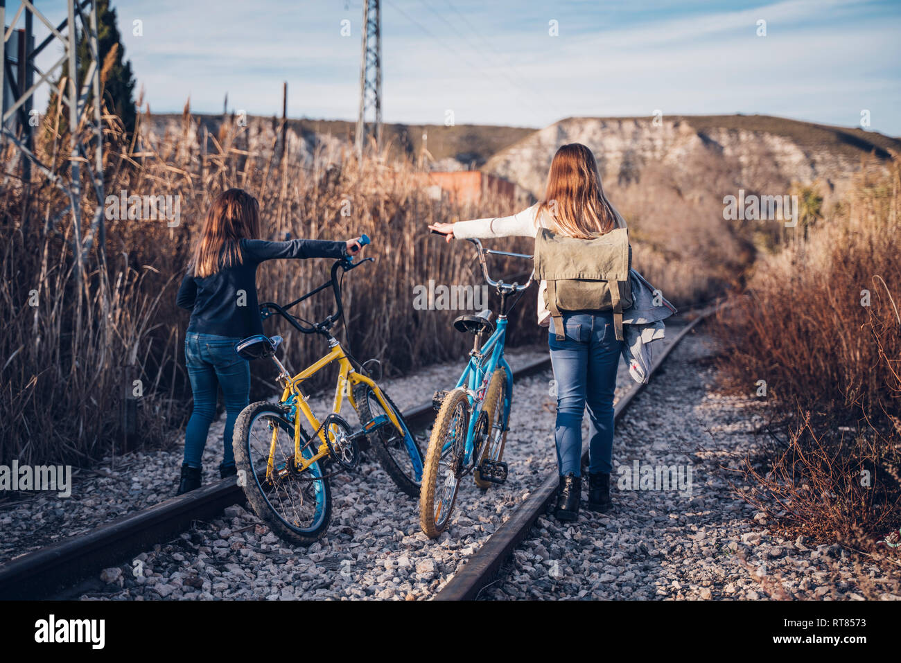 Two girls walking on the train track with bicycles Stock Photo