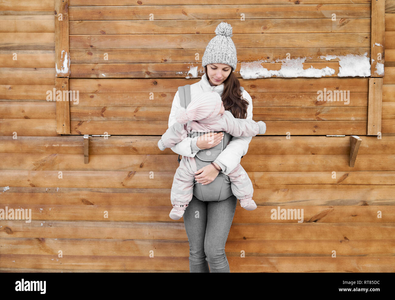 Little baby girl and her mother babywearing in the ergo carrier in