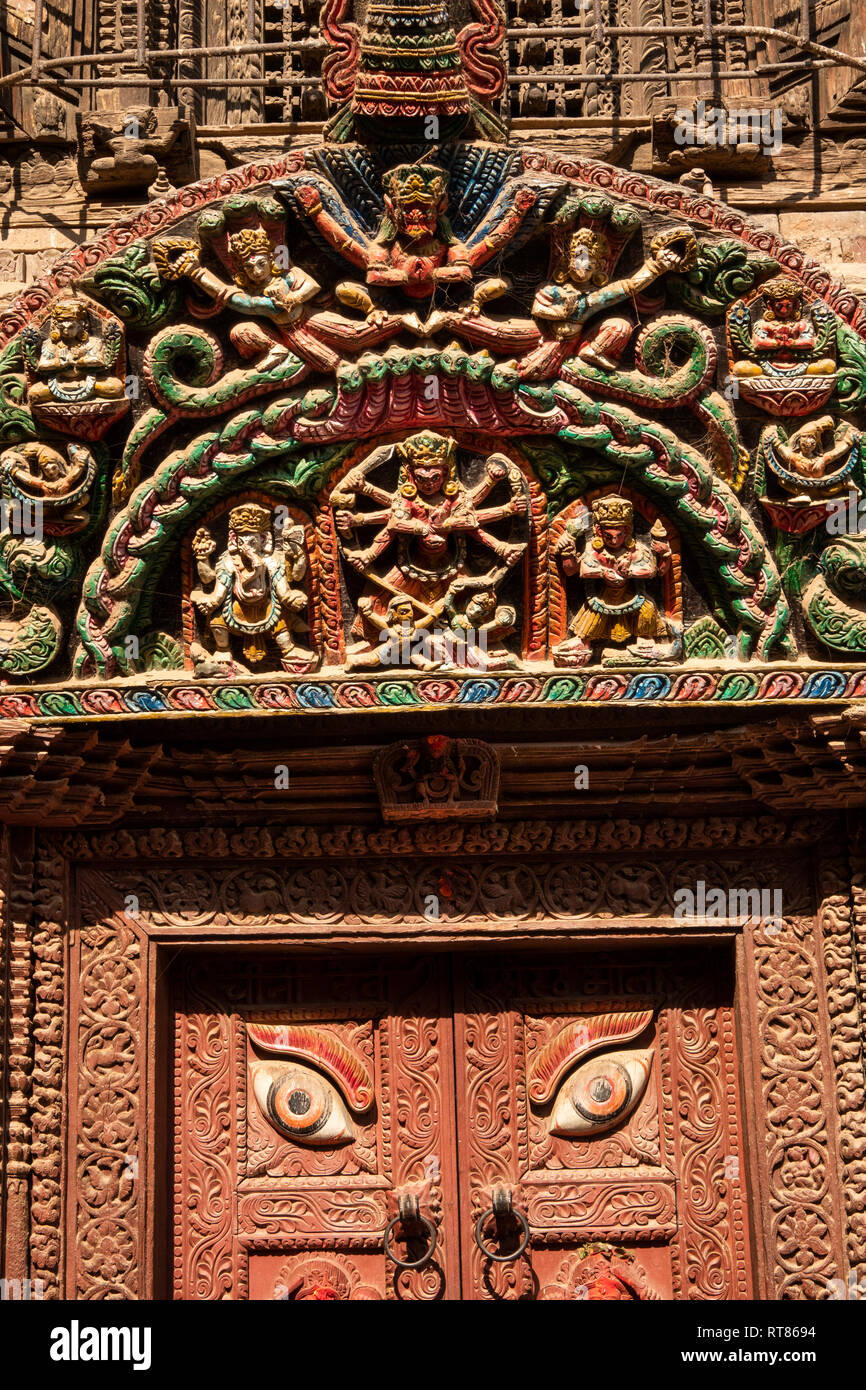 Nepal, Kathmandu Valley, Bhaktapur, crudely carved and painted torana above rebuilt temple doorway Stock Photo