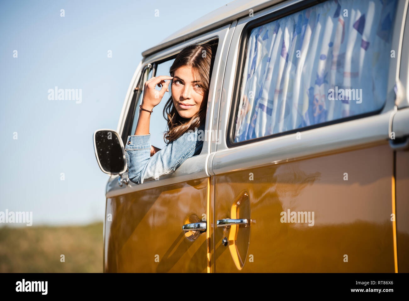 Pretty woman on a road trip with her camper, looking out of car window ...