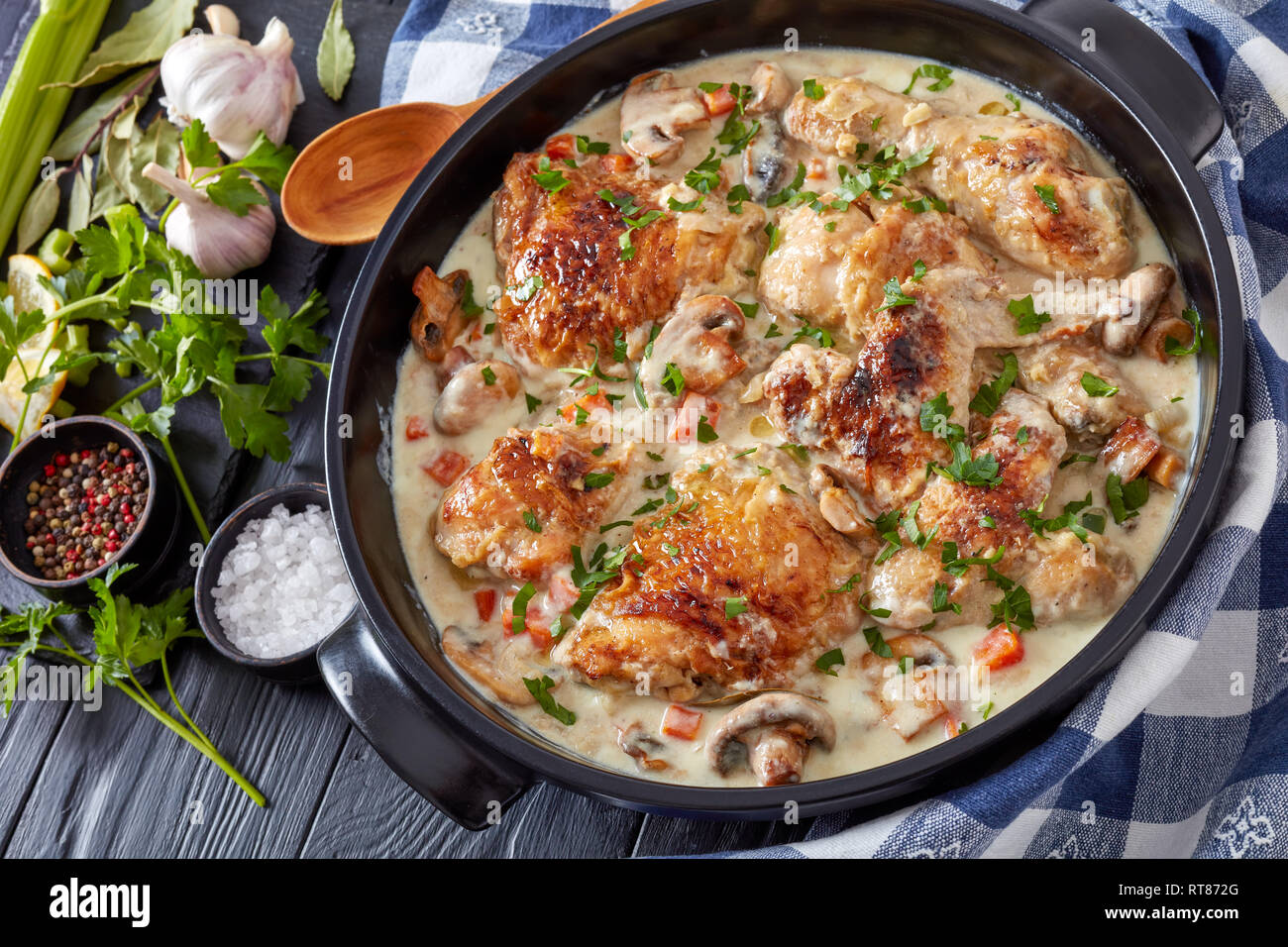 chicken fricassee in a black dutch oven - chicken meat browned and stewed in white wine creamy sauce with mushrooms and vegetables, classic french rec Stock Photo