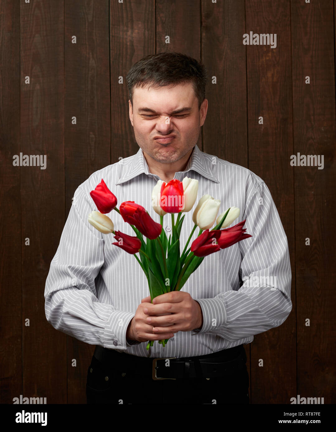 Man holds red flowers bouquet with awful smell Stock Photo Alamy