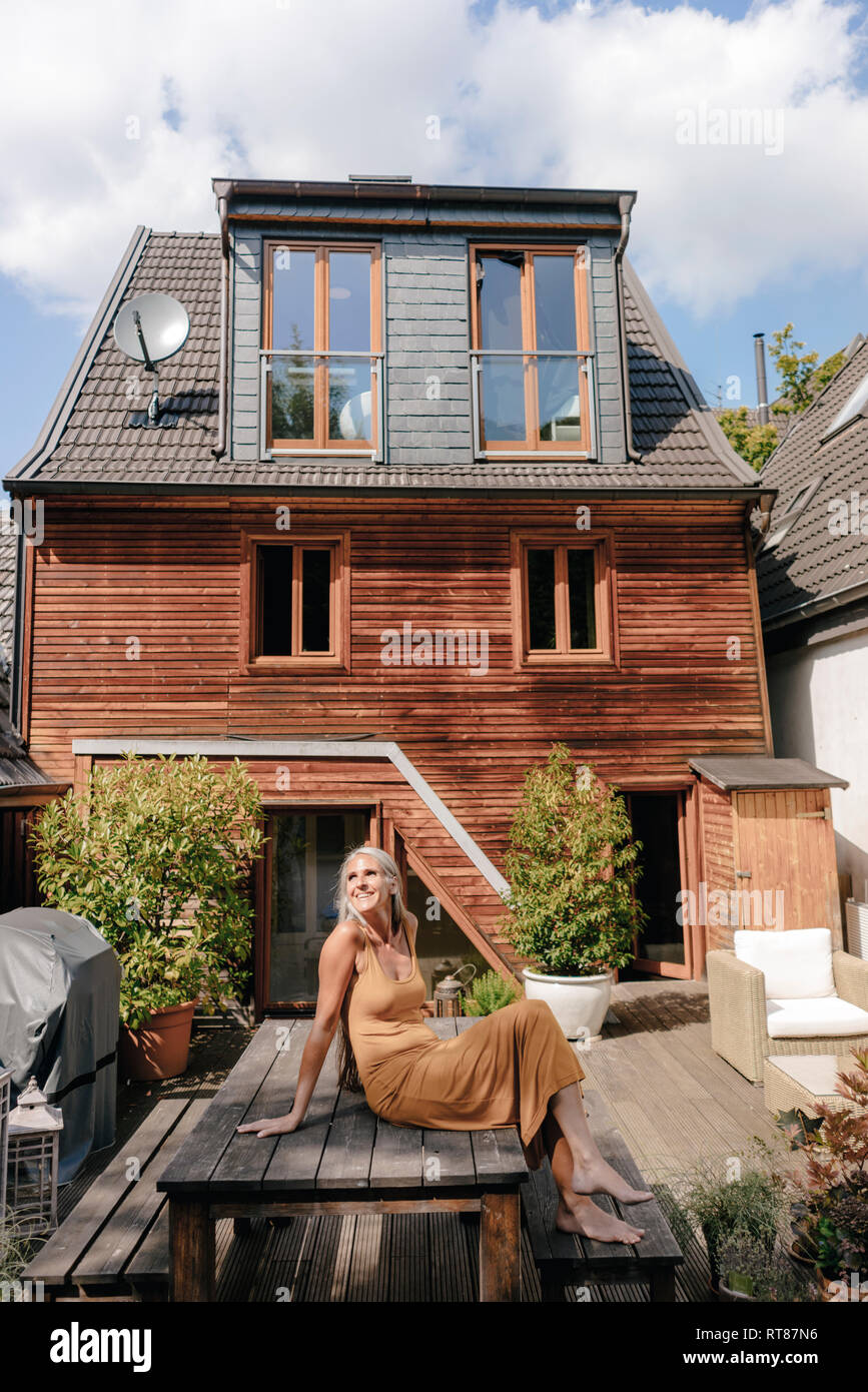 Happy woman sitting on terrace of her house Stock Photo - Alamy