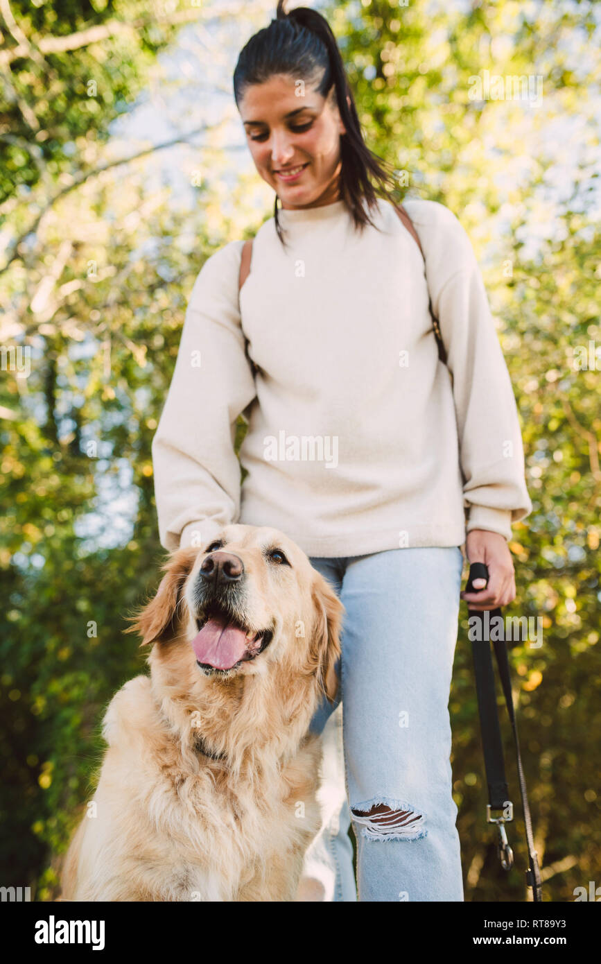 Smiling young woman with her Golden retriever dog in a park Stock Photo ...