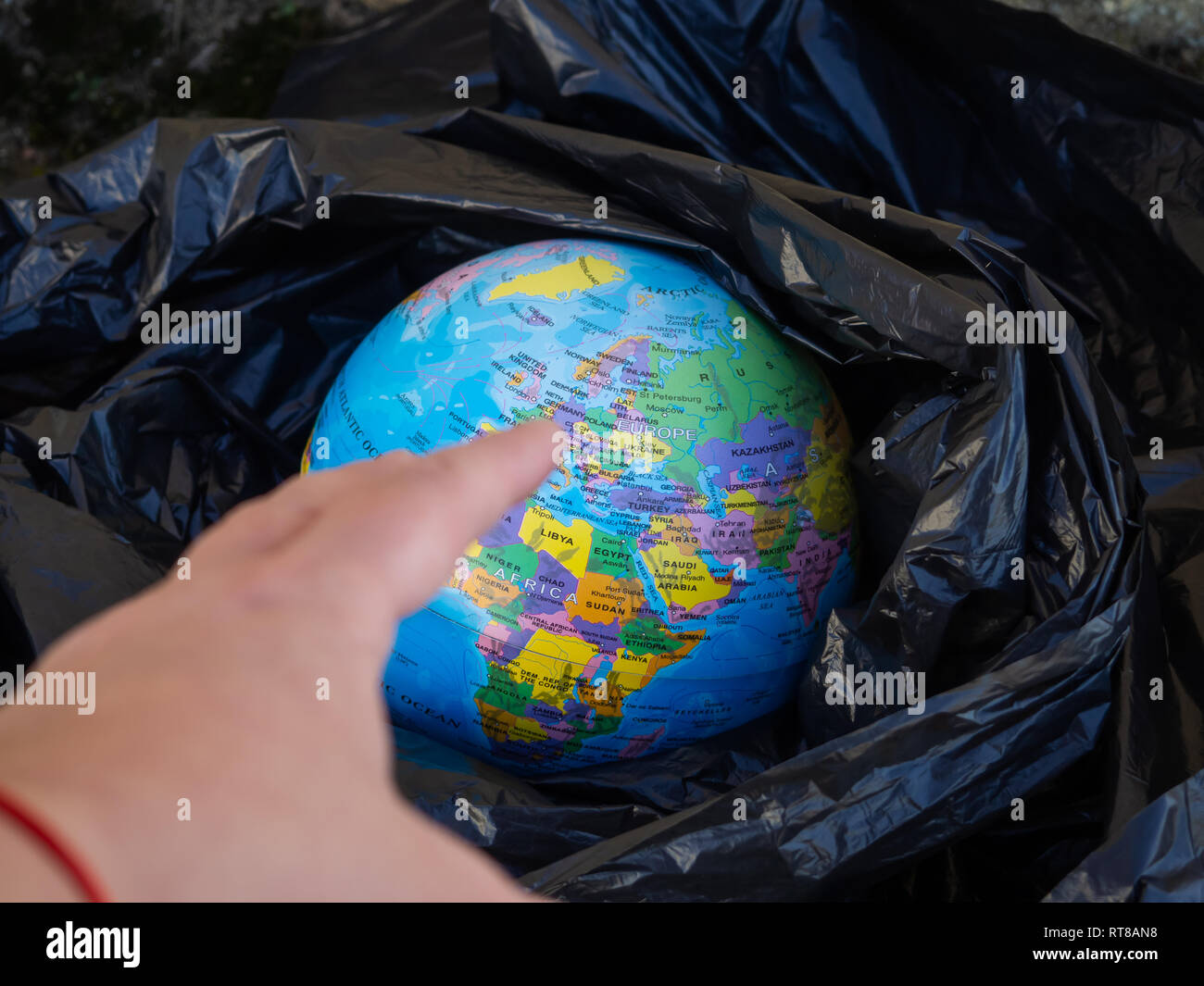 A person touching a terrestrial globe or planet Earth near a plastic bag. Ecology concept Stock Photo