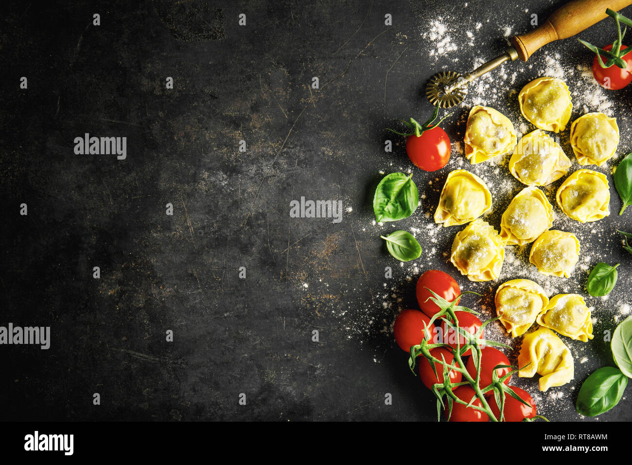 Food background. Italian food background with ravioli, tomatoes, olives and basil on dark background. Horizontal with copy space. Stock Photo