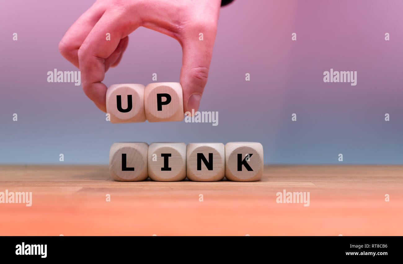 Dice form the word 'UPLINK' while a hand rises the letters 'UP'. Stock Photo
