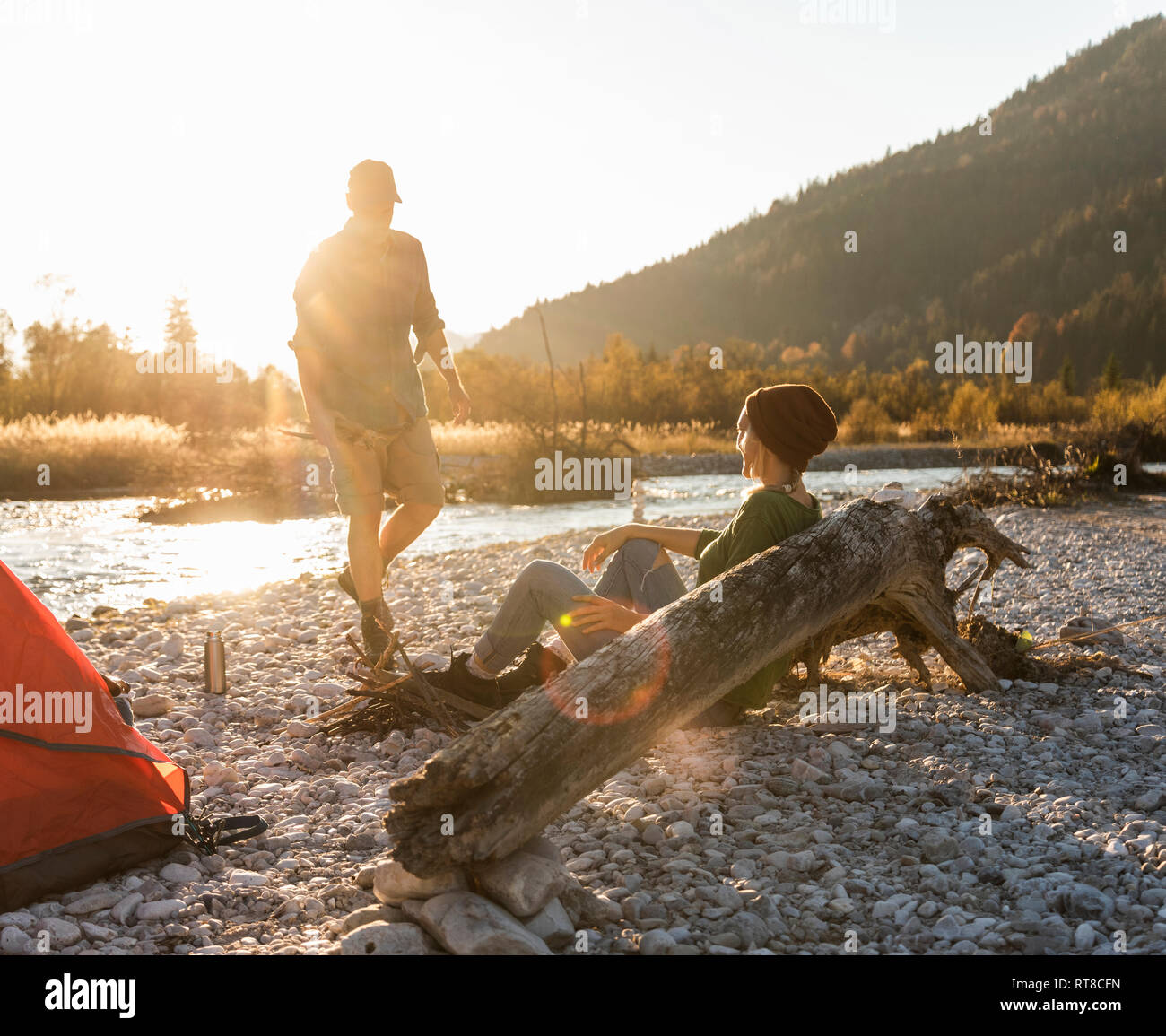 Mature couple camping at riverside, collecting wood for a camp fire Stock Photo