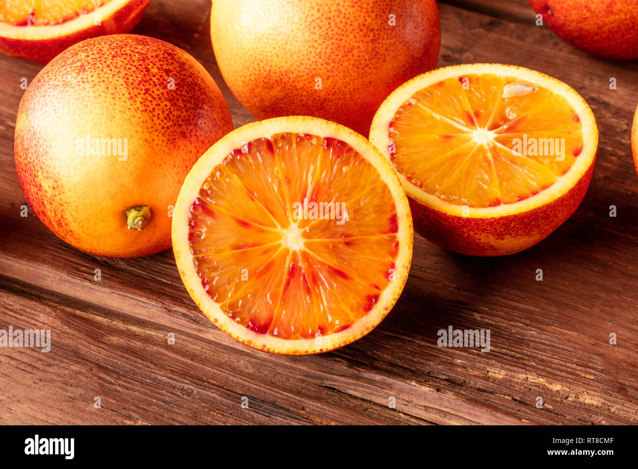 A closeup photo of an organic blood orange on a dark rustic wooden ...