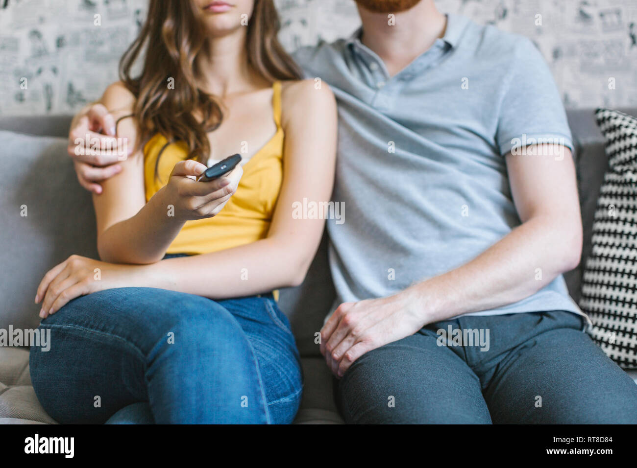 Couple sitting on couch watching TV, partial view Stock Photo