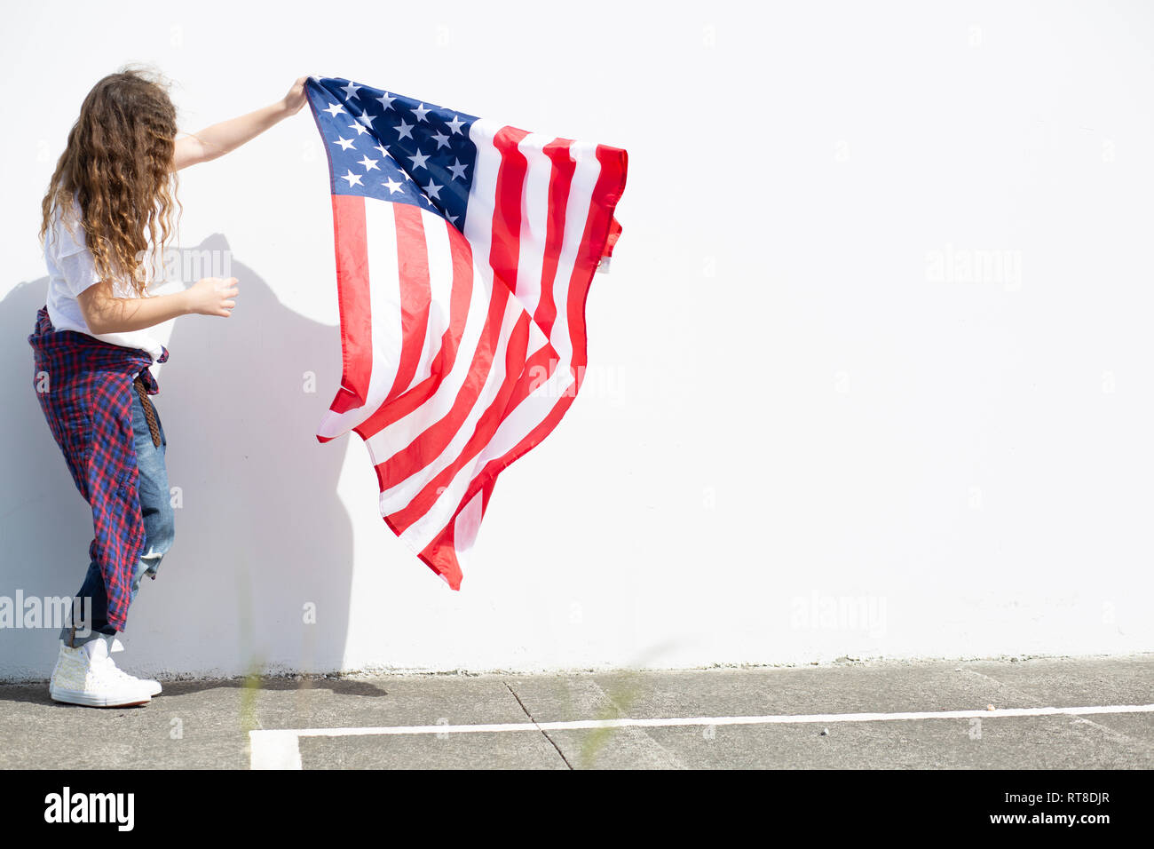 Girl holding American flag at white wall Stock Photo - Alamy