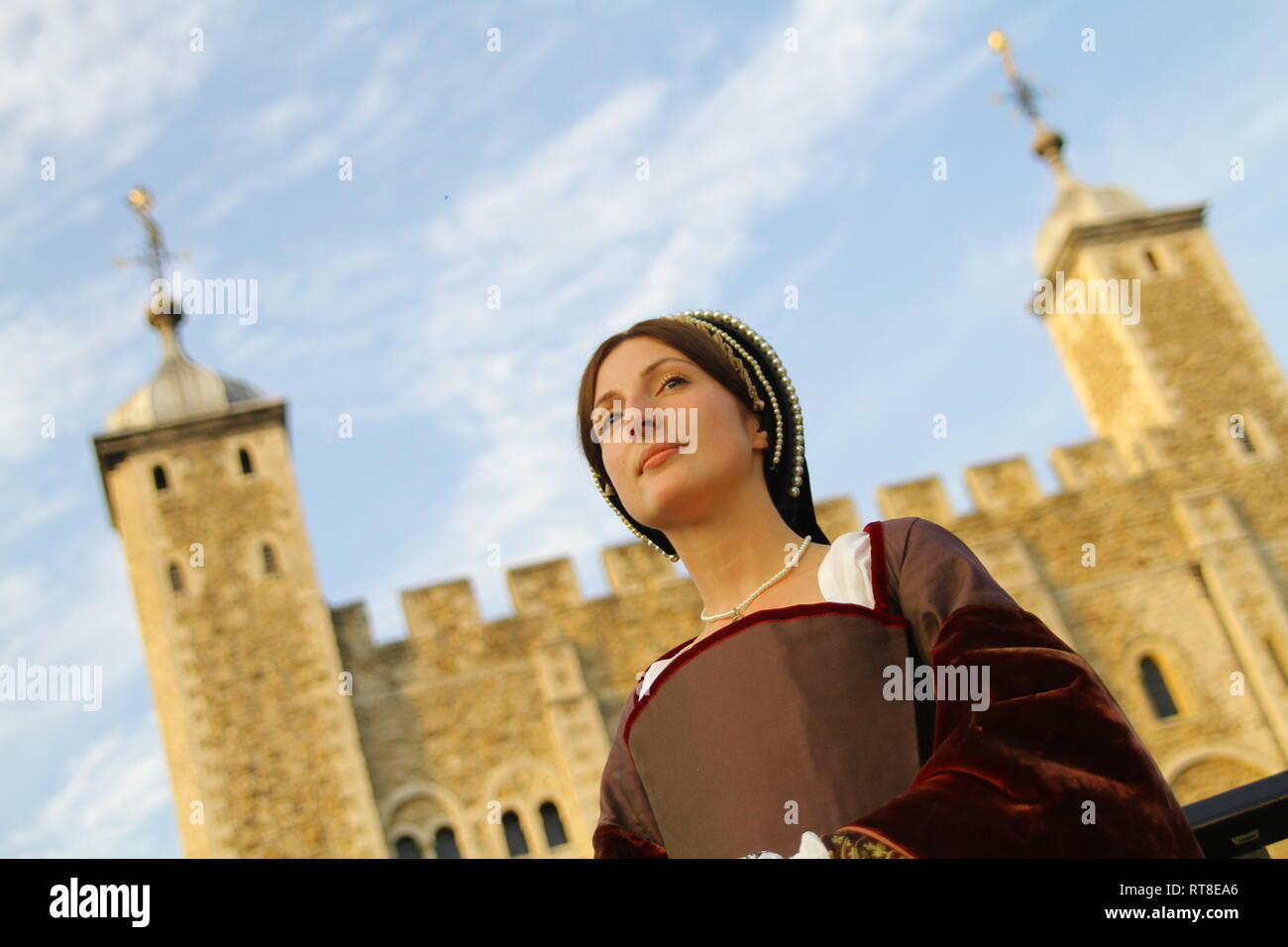 A woman dressed as Anne Boleyn stands in front of the Tower of London- she is a beautiful modern day woman in authentic dress Stock Photo